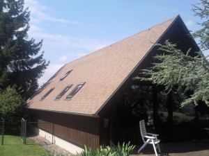 Haus mit Holzfassade und braunrotem Dach