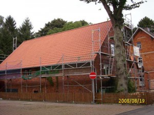 Backsteinhaus mit rotem Dach und Baugerüst