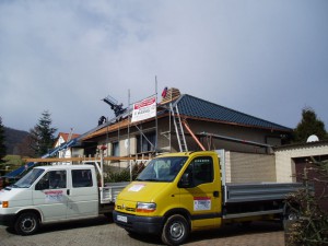 Beiges Haus mit schwarzem Dach; davor Hannig Firmenfahrzeuge