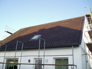 Weißes Haus mit braunem Dach und Baugerüst