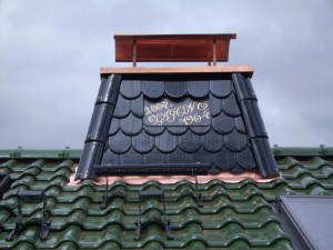 Schwarzer Schornstein mit Zierpfanne mit goldenem Schriftzug